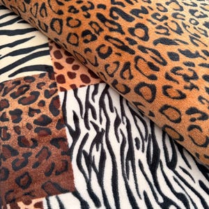 Peut inclure: Gros plan sur un tissu avec un motif patchwork présentant des imprimés animaliers. Les motifs comprennent des taches de léopard marron et noir, des rayures zébrées noires et blanches et un imprimé guépard marron et beige.