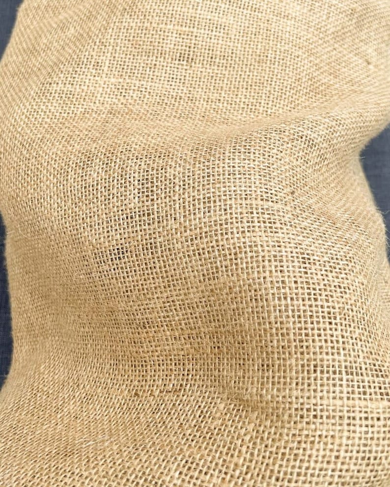 May include: A close-up of a natural brown burlap fabric with a woven texture.