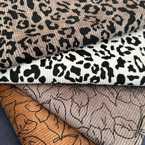 Op de afbeelding: Close-up van verschillende stofstalen. De bovenste twee stalen hebben een luipaardprint in bruin en zwart, en zwart en wit. De onderste twee hebben een ribfluweel textuur met een bladmotief in bruin en beige.
