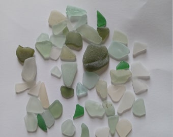 Könnte beinhalten: Eine Sammlung von Meerglas in verschiedenen Grüntönen, Blau- und Weißtönen. Die Glassplitter sind glatt und wurden vom Meer geschliffen.