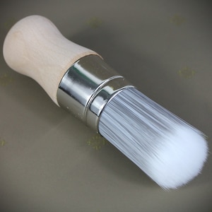Könnte beinhalten: Ein weißer Pinsel mit einem Holzgriff und einer silbernen Metallzwinge. Der Pinsel ist neu und unbenutzt.