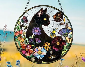May include: A stained glass window hanging features a black cat with yellow eyes surrounded by colorful flowers. The cat is looking to the right. The window is circular and has a metal frame.
