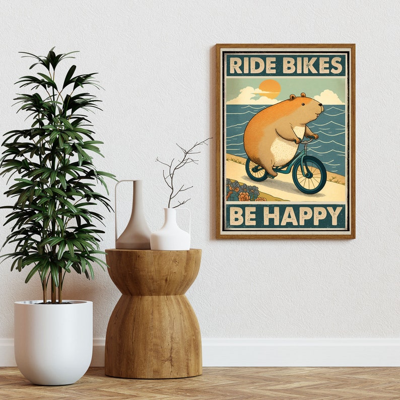 Puede incluir: Un p&oacute;ster de estilo vintage con un h&aacute;mster de dibujos animados montando una bicicleta en una playa. El p&oacute;ster tiene el texto "Ride Bikes Be Happy" en una fuente retro.