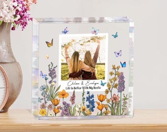 May include: A clear acrylic photo block with a photo of two people with their arms raised. The block is decorated with colorful butterflies and floral designs. Text reads "Chloe & Evelyn" and "Life is Better With My Bestie."