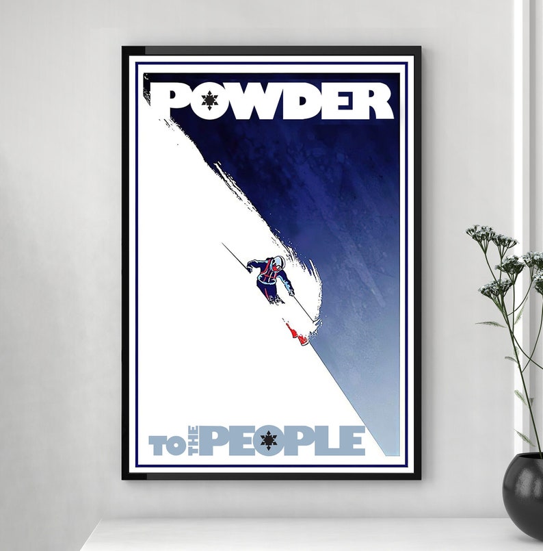 May include: A vintage-style poster with a blue and white color scheme. The poster features a skier in a blue and red suit skiing down a snowy slope. The text "POWDER TO THE PEOPLE" is printed in white letters on the poster.