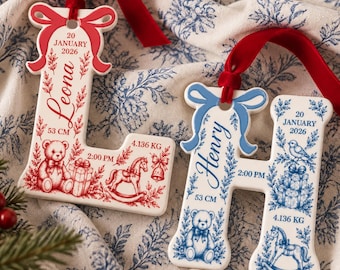 May include: Two ceramic letter ornaments, L and H, with red and blue velvet ribbons. The L features red ink with the name Leona, 20 January 2026, 53 cm, 2:00 PM, 4.136 kg, a teddy bear, and a rocking horse. The H features blue ink with Henry, 20 January 2026, 53 cm, 2:00 PM, 4.136 kg, a bird, and a rocking horse.