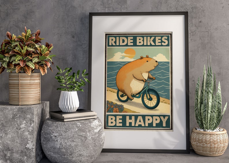 Puede incluir: Un p&oacute;ster de estilo vintage con un h&aacute;mster de dibujos animados montando una bicicleta con el texto "Ride Bikes Be Happy". El p&oacute;ster tiene un esquema de color azul, verde y amarillo y est&aacute; enmarcado en un marco negro.