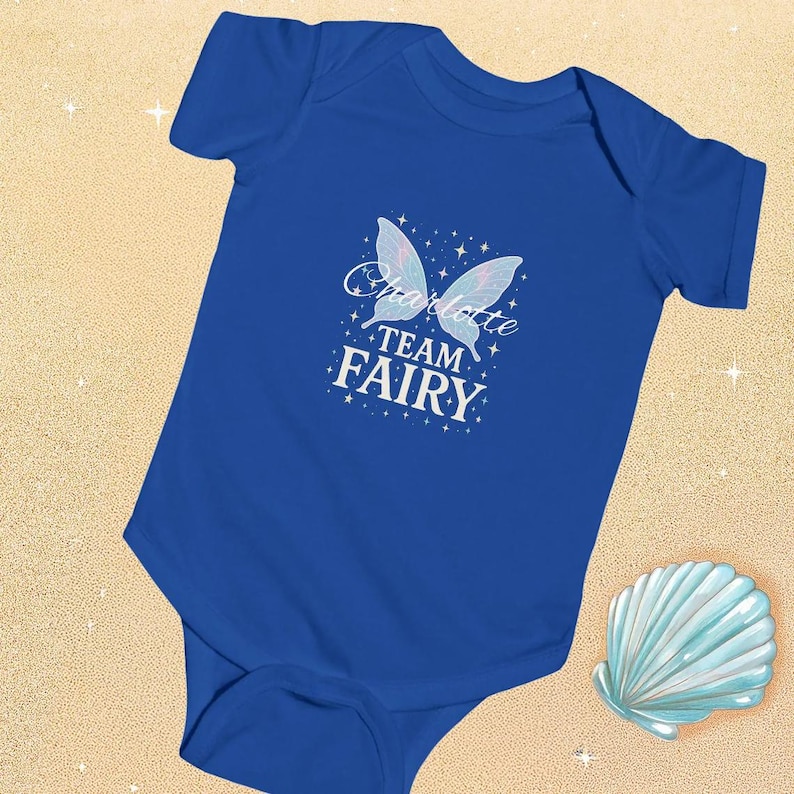 Royal Blue Baby Bodysuit on a sandy beach with Team Fairy and the name Charlotte written across the wings