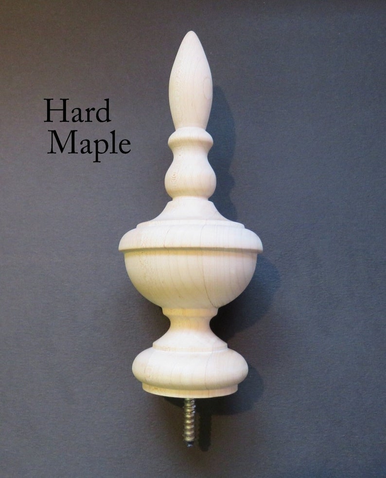May include: A wooden finial with a pointed top and a bulbous base. The finial is made of hard maple and has a natural finish. It is attached to a screw.