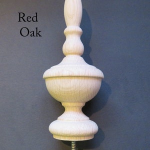 May include: A wooden finial with a pointed top and a bulbous base. The finial is made of red oak and has a natural finish. It is designed to be attached to a piece of furniture or other object.