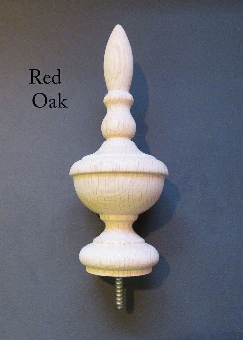 May include: A wooden finial with a pointed top and a bulbous base. The finial is made of red oak and has a natural finish. It is designed to be attached to a piece of furniture or other object.