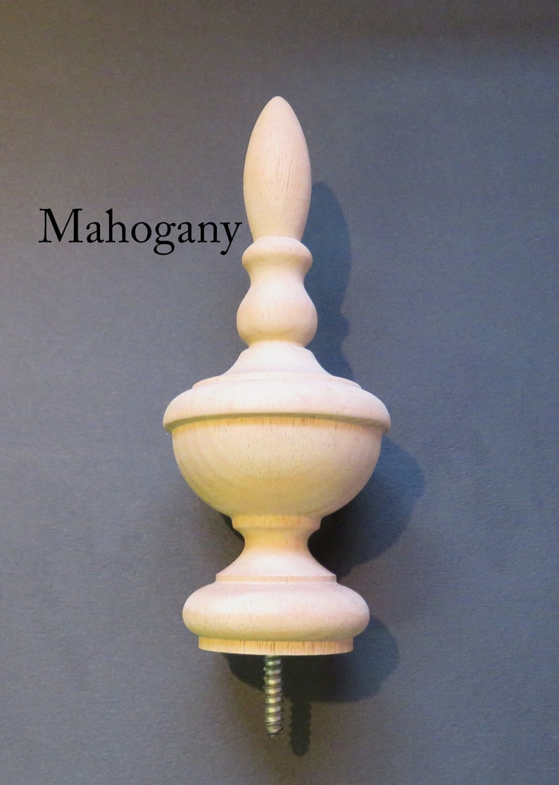 May include: A light wood finial with a bulbous shape and a pointed top. The finial has a screw on the bottom. "Mahogany" is written in black text on the left side of the image.