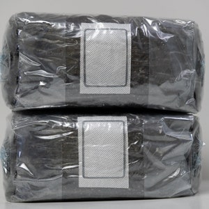 May include: Two black rectangular packages wrapped in clear plastic with a white label on each package.