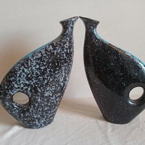 May include: A set of three ceramic vases in varying heights and shapes. The vases feature a matte white finish and a minimalist design, suitable for displaying flowers or as decorative objects.