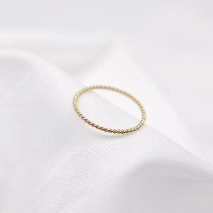 Pode incluir: Um fino anel de ouro com um design trançado.