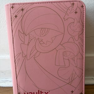 May include: A pink rectangular trading card binder with a textured surface. The front cover features a dark pink line art illustration of two stylized creatures and the text vaultx in the bottom left corner, accented by small star shapes.