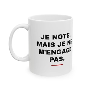 May include: A white ceramic mug featuring the black printed text "JE NOTE, MAIS JE NE M'ENGAGE PAS." with a small horizontal red line underneath the text. The mug has a curved handle on the left side and a smooth, cylindrical body design.