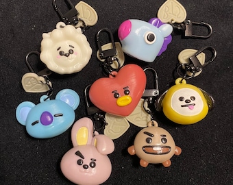 May include: A set of seven colorful keychains featuring cartoon characters. The keychains are made of plastic and have a variety of shapes, including a heart, a bear, a bunny, a dog, and a bird. The keychains are attached to metal rings.