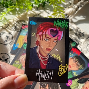 Puede incluir: Una tarjeta ilustrada en blanco y negro con un personaje de dibujos animados con cabello rojo que lleva gafas de corazón rosa y un collar de perlas. La tarjeta tiene el texto "WARNING" y "HYUNJIN".