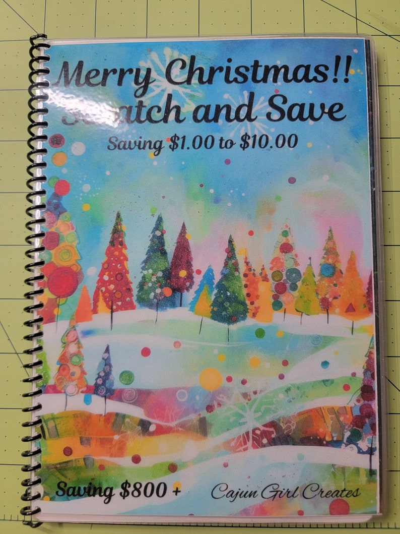 May include: A colorful Christmas-themed scratch and save booklet with a winter wonderland scene featuring trees, snow, and colorful dots. The text on the cover reads "Merry Christmas!! Scratch and Save Saving $1.00 to $10.00 Saving $800+ Cajun Girl Creates".