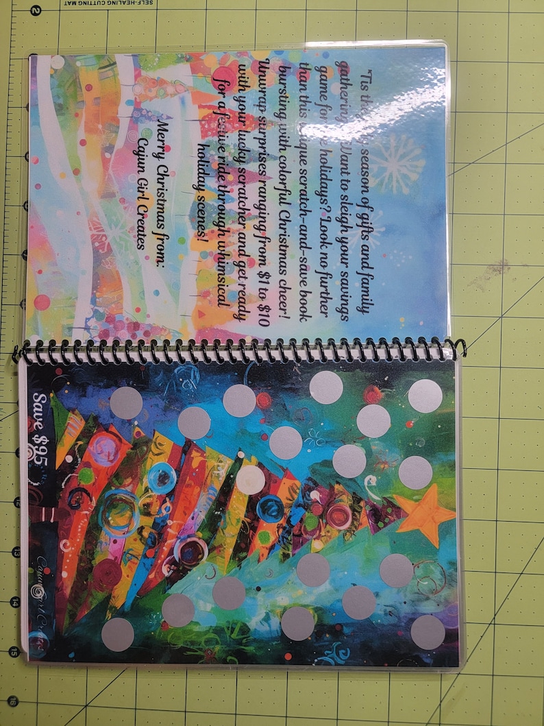May include: A colorful Christmas-themed scratch-and-save book with a festive tree design. The book has silver circles that can be scratched to reveal discounts. The text on the book reads "Tis the season of gifts and family gathering...Want to sleigh your savings game for holidays? Look no further than this unique scratch-and-save book bursting with colorful Christmas cheer! Unwrap surprises ranging from $1 to $10 with your lucky scratcher and get ready for a festive ride through whimsical holiday scenes! Merry Christmas from: Cajun Girl Creates Save $95"