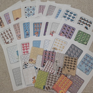 May include: A selection of sticker sheets with cartoon characters and patterns, presented in white paper packaging. Designs include hearts, umbrellas, and character faces. The text "Copey Girl Crafts" is visible on some sheets.