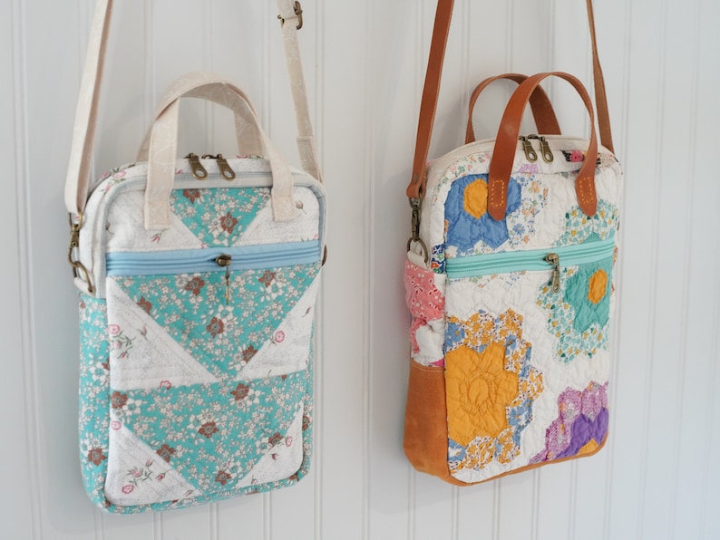 May include: Two quilted fabric shoulder bags with floral patterns. One bag features turquoise and white floral triangles, a light blue zipper, and a cream-colored handle. The other bag has a brown leather handle and base, with colorful floral patches.