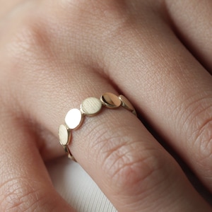 Peut inclure: Une bague en or avec une rangée de petits disques plats et ronds.