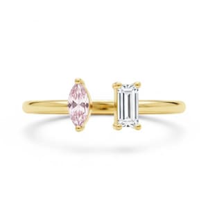 May include: A gold ring with a pink, marquise-cut gemstone and a white, emerald-cut gemstone. The ring has a slender band and a modern design, suitable for everyday wear. The gemstones are set side by side.