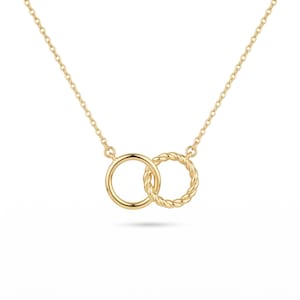 May include: A gold-toned necklace featuring two interlocking circular pendants suspended from a delicate chain. One circle has a smooth, polished surface, while the other circle features a twisted, rope-like texture. The metal has a bright finish.