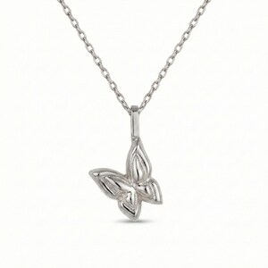 May include: A silver-colored butterfly pendant necklace. The butterfly pendant has detailed wing designs and hangs from a delicate chain. The necklace is displayed against a white background.