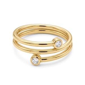 Puede incluir: Un anillo de oro con un diseño de espiral de doble banda. Los dos extremos de la banda están rematados con diamantes blancos redondos engastados en bisel, creando una superficie pulida y reflectante en la estructura de oro amarillo.