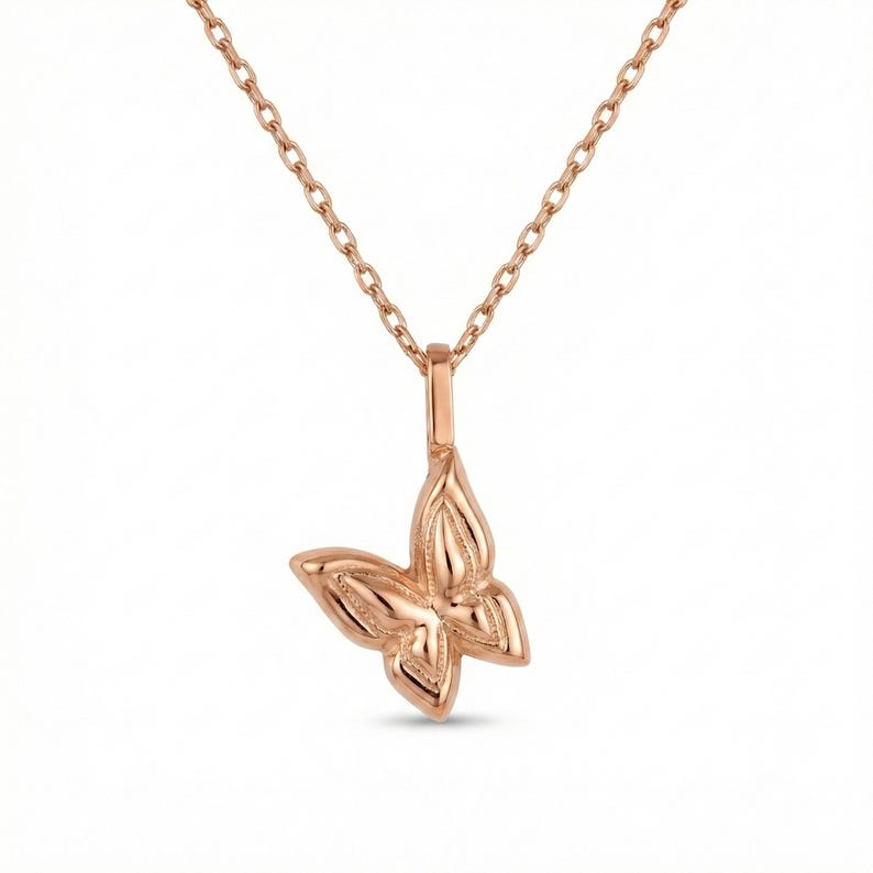 May include: A rose gold butterfly pendant necklace. The butterfly pendant is detailed with textured wings and hangs from a delicate chain. The necklace is displayed against a white background.