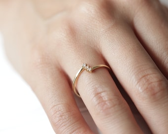 May include: A gold ring with three small diamonds set in a curved band.