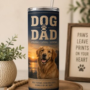 May include: A navy blue tumbler with a golden retriever image and the words "DOG DAD" in white. The tumbler also features the phrases "STRONG • LOYAL • LOVING" and "BEST FRIEND. FOREVER LOYAL ALWAYS BY MY SIDE."