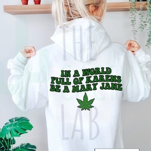 May include: White hoodie with the text "In a world full of Karens be a Mary Jane" and a green marijuana leaf graphic. The text "The Cactus Lab" is printed on the bottom right corner of the hoodie.