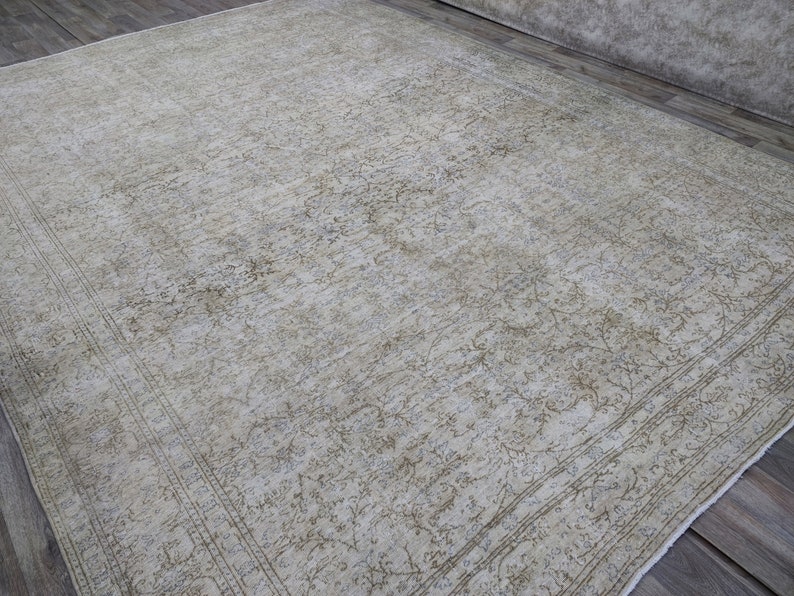 May include: A vintage rug with a light beige background and a faded floral pattern in a darker beige color. The rug has a border with a more intricate design.