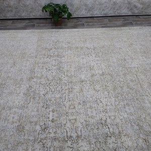 May include: A light beige area rug with a subtle, distressed floral pattern. The rug has a soft, faded look, giving it a vintage feel.