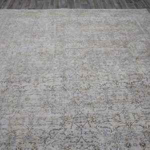 May include: A beige area rug with a light brown and gray floral pattern. The rug has a distressed look and is made of a soft, woven material.