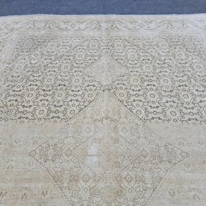 May include: A cream-colored rug with a geometric pattern in black. The pattern is made up of repeating shapes and lines.