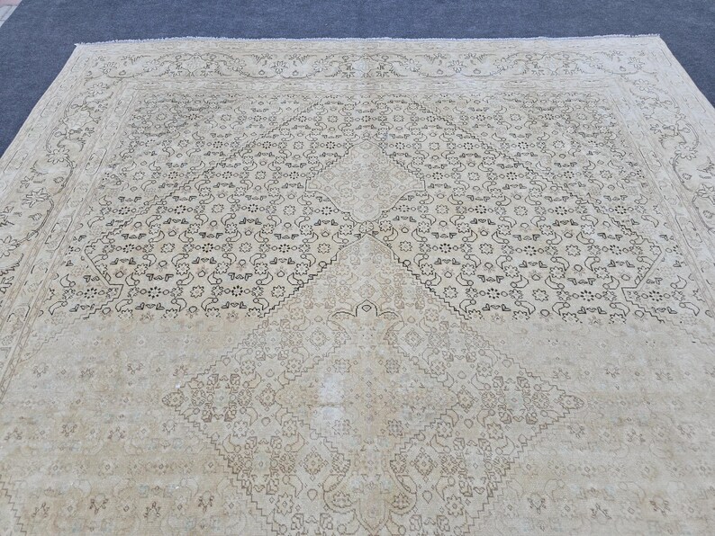 May include: A cream-colored rug with a geometric pattern in black. The pattern is made up of repeating shapes and lines.