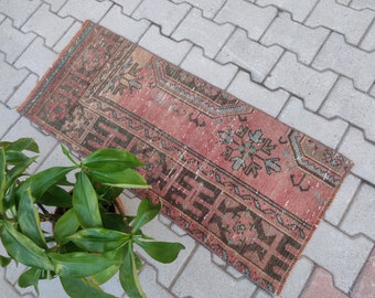 May include: A vintage Turkish runner rug with a faded pink background and intricate geometric patterns in shades of brown, blue, and green. The rug is laid out on a gray concrete patio.