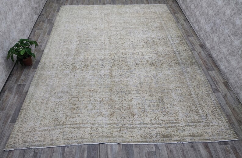 May include: A vintage rug with a faded floral pattern in shades of beige and green. The rug has a distressed look and a worn border.
