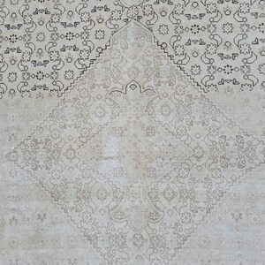 May include: A white rug with a delicate, intricate pattern of black floral designs. The pattern is symmetrical and creates a diamond shape in the center of the rug.