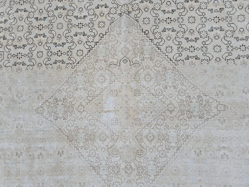 May include: A white rug with a delicate, intricate pattern of black floral designs. The pattern is symmetrical and creates a diamond shape in the center of the rug.