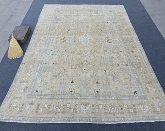 May include: A large rectangular area rug featuring a beige background with intricate patterns in light blue, cream, and dark brown. The design includes a central diamond medallion, elaborate floral motifs, and a detailed border with fringe edges.