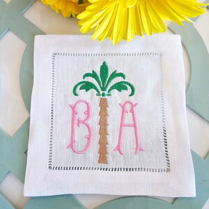 Peut inclure: Serviette en lin blanc avec un palmier vert et les lettres brodées roses "BIA".