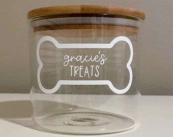 May include: A clear glass jar with a bamboo lid, labeled "gracie's treats" in a white bone-shaped design.
