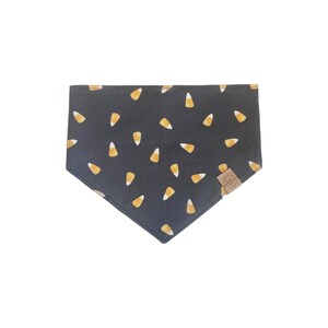 Puede incluir: Bandana negra con un patr&oacute;n de ma&iacute;z dulce amarillo y naranja. La bandana tiene una peque&ntilde;a etiqueta marr&oacute;n con el texto "Puddles" en ella.