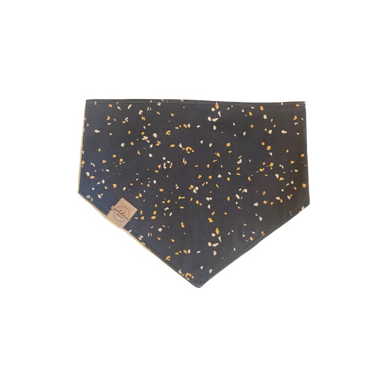 Puede incluir: Un pa&ntilde;uelo negro con un patr&oacute;n moteado blanco y amarillo. El pa&ntilde;uelo tiene una peque&ntilde;a etiqueta marr&oacute;n con la palabra "Wildhorn" en ella.